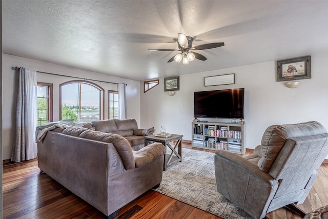 living room featuring ceiling fan, dark wood-type flooring, and a textured ceiling