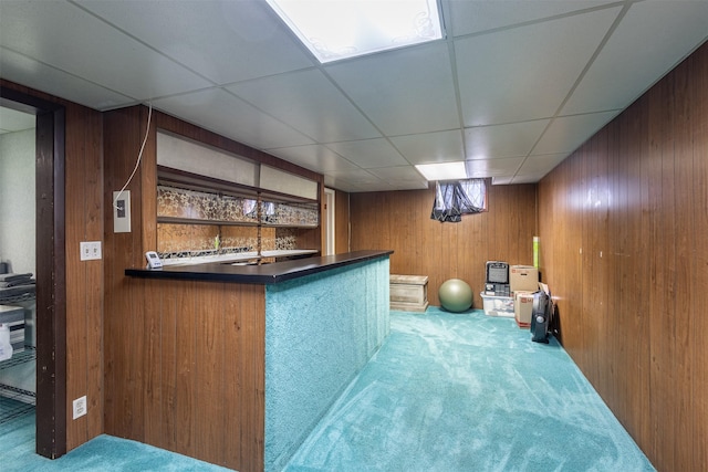 bar with carpet floors, a drop ceiling, and wood walls