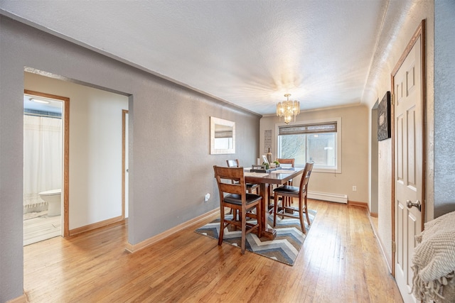 dining room with light wood-type flooring, an inviting chandelier, crown molding, and a baseboard radiator