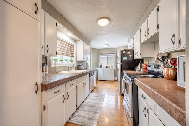 kitchen featuring white cabinetry, stainless steel appliances, a textured ceiling, light hardwood / wood-style flooring, and sink