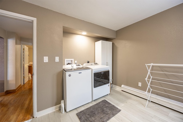 laundry room featuring cabinets, separate washer and dryer, baseboard heating, and light hardwood / wood-style flooring