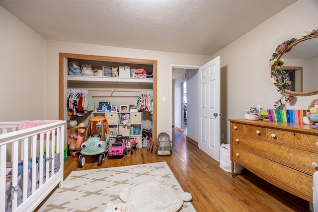 bedroom with a textured ceiling, a closet, and hardwood / wood-style floors