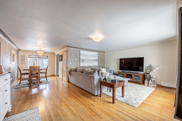 living room featuring light wood-type flooring, baseboard heating, an inviting chandelier, and a textured ceiling