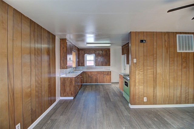 kitchen with wooden walls, sink, dark hardwood / wood-style floors, stainless steel electric range oven, and ceiling fan