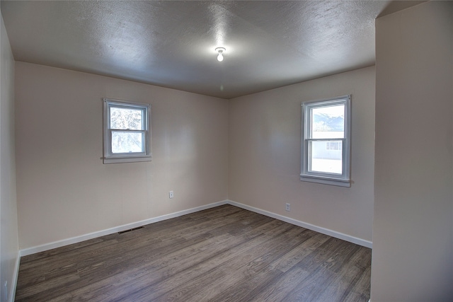 unfurnished room featuring a textured ceiling, dark wood-type flooring, and a healthy amount of sunlight