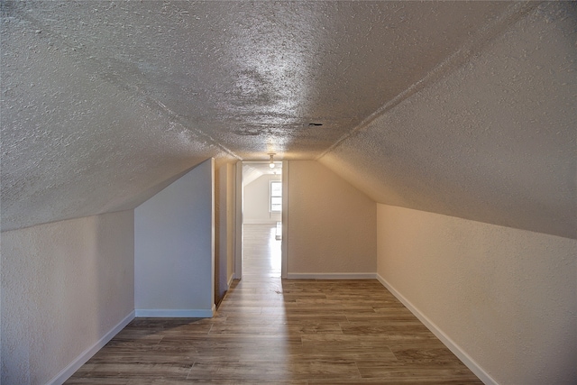 additional living space featuring wood-type flooring, lofted ceiling, and a textured ceiling