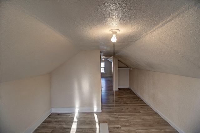 bonus room featuring vaulted ceiling, dark wood-type flooring, and a textured ceiling