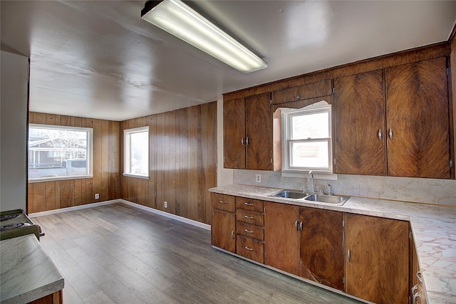 kitchen featuring a wealth of natural light, light hardwood / wood-style flooring, wooden walls, and sink