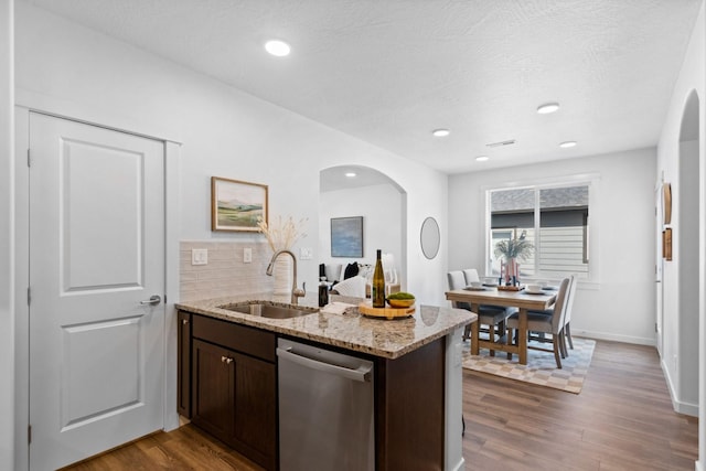 kitchen with dishwasher, dark wood-type flooring, sink, kitchen peninsula, and light stone counters