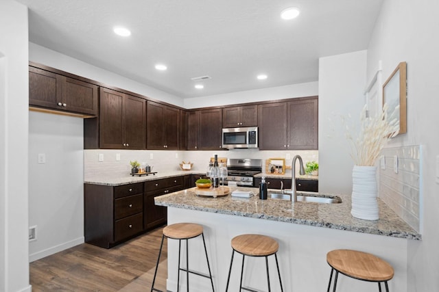 5843 Horn Rd, Missoula, MT 59808 - kitchen featuring stainless steel appliances, a peninsula, dark brown cabinets, light stone countertops, and recessed lighting