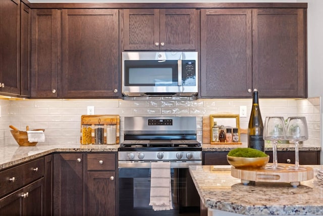 kitchen featuring light stone countertops, decorative backsplash, appliances with stainless steel finishes, and dark brown cabinetry