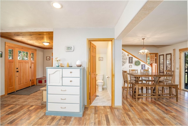 interior space featuring light wood-type flooring, an inviting chandelier, white cabinetry, and decorative light fixtures