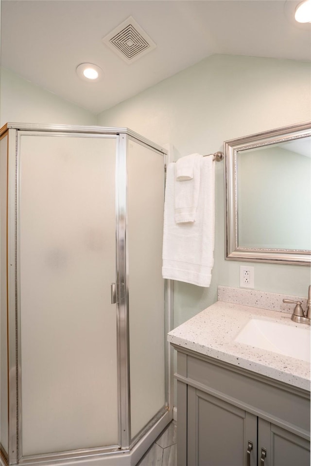 bathroom featuring a shower with shower door, vanity, and vaulted ceiling