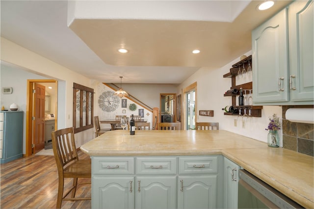 kitchen with kitchen peninsula, dark hardwood / wood-style flooring, hanging light fixtures, a breakfast bar, and dishwashing machine