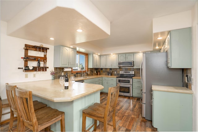 7 Hardy Cir, Ennis, MT 59729 - kitchen with a peninsula, stainless steel appliances, a breakfast bar, tasteful backsplash, and dark wood finished floors