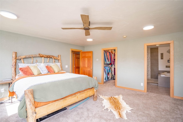 carpeted bedroom featuring a spacious closet, ceiling fan, ensuite bathroom, and a closet