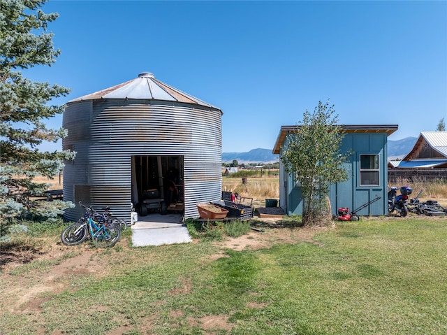 back of house with a mountain view, a lawn, and an outdoor structure