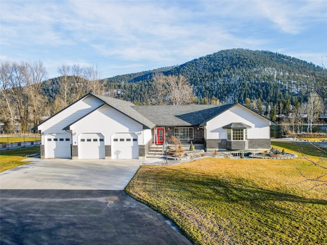 view of front facade with a garage, a front lawn, and a mountain view