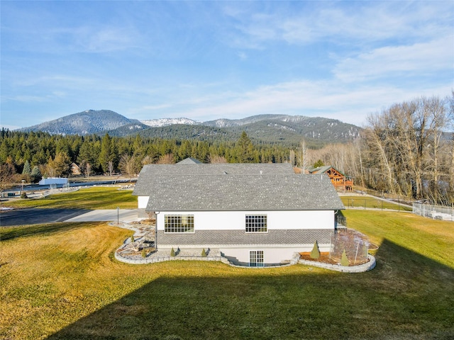 back of property with a mountain view and a lawn