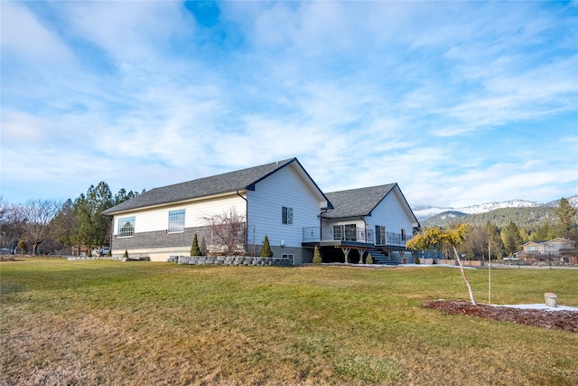 rear view of property featuring a lawn and a deck with mountain view