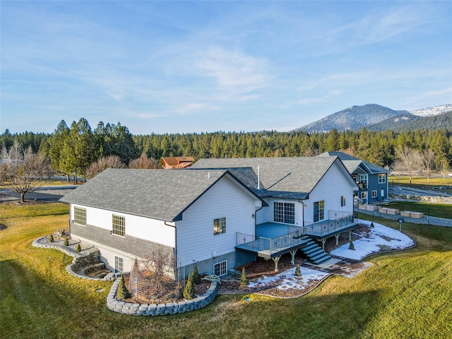 rear view of property featuring a deck with mountain view and a lawn