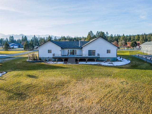 back of property with a deck with mountain view and a yard