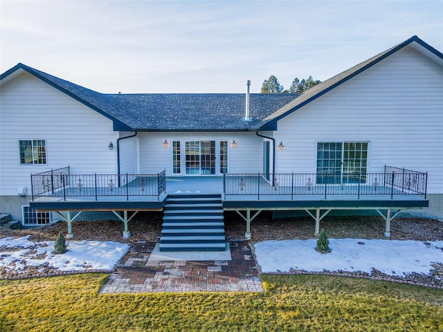 snow covered property featuring a wooden deck and a lawn