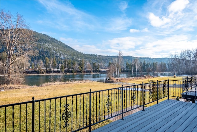 wooden deck featuring a water and mountain view and a yard