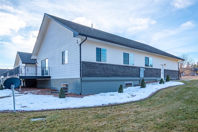 snow covered property featuring a wooden deck and a lawn