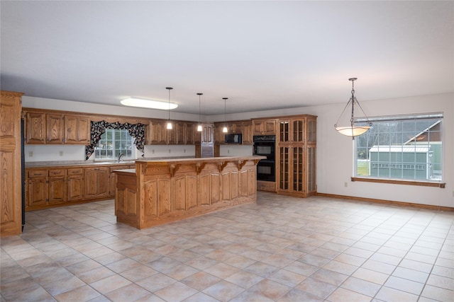 kitchen with pendant lighting, black appliances, a breakfast bar, a center island, and sink