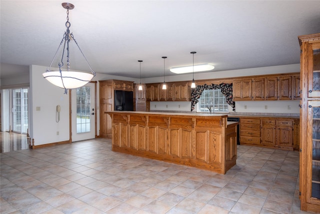 kitchen with black fridge with ice dispenser, decorative light fixtures, and a center island