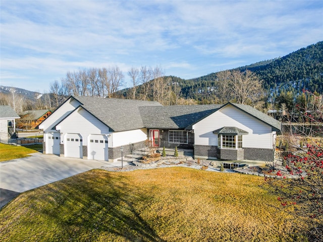 ranch-style home featuring a garage, a front lawn, and a mountain view