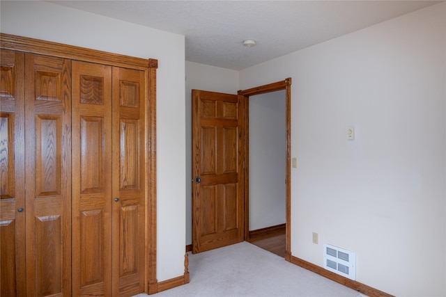 unfurnished bedroom with light colored carpet and a closet