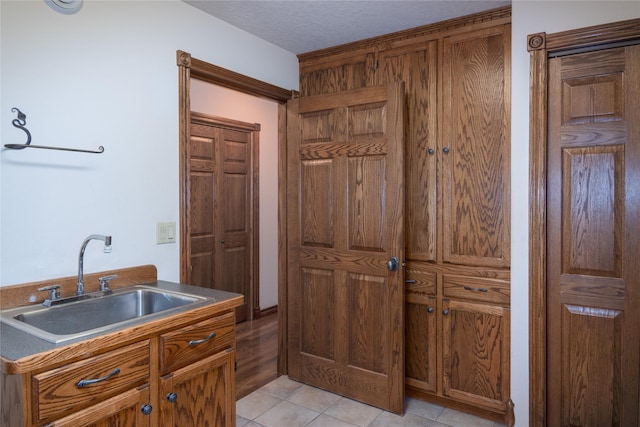 interior space featuring sink, a textured ceiling, and light tile patterned flooring