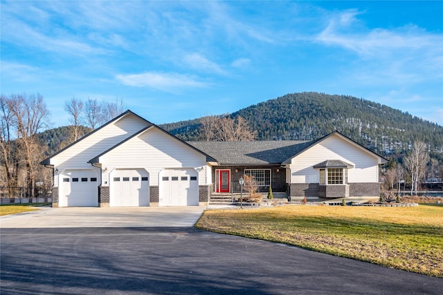 single story home featuring a garage, a front lawn, and a mountain view