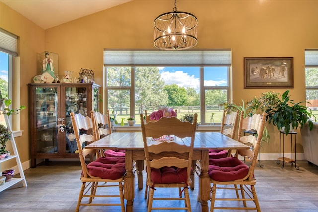 dining room featuring plenty of natural light, wood-type flooring, lofted ceiling, and a chandelier