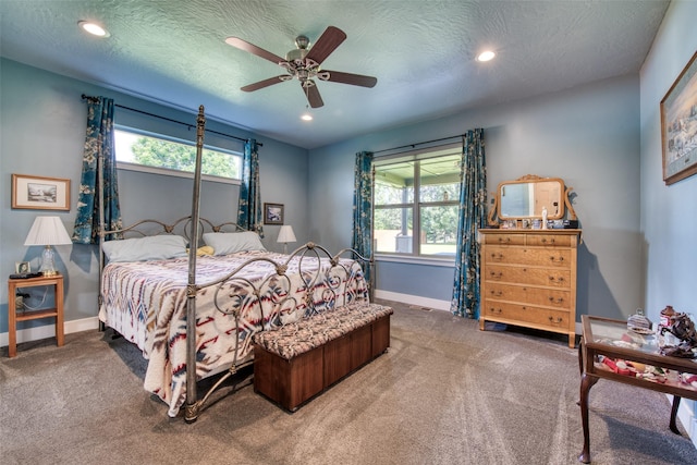 carpeted bedroom with ceiling fan, multiple windows, and a textured ceiling