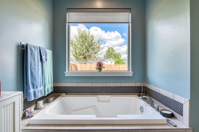 bathroom featuring tiled bath and a healthy amount of sunlight