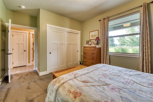 bedroom featuring a textured ceiling, a closet, and light colored carpet