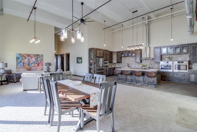 carpeted dining area featuring sink and a high ceiling