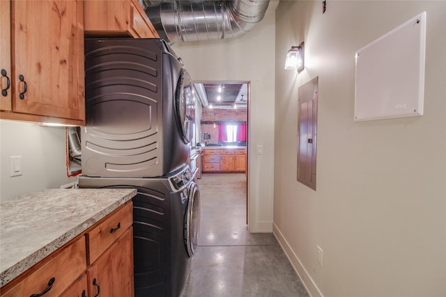 laundry area with stacked washer and dryer, electric panel, and cabinets