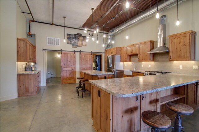 kitchen with stainless steel fridge, hanging light fixtures, a center island, a high ceiling, and a barn door