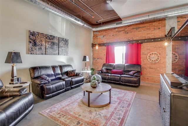 living room with concrete flooring, brick wall, and a towering ceiling