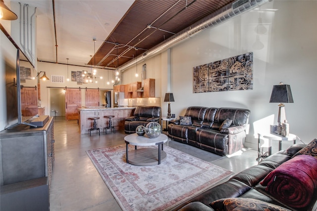 living room featuring a barn door, concrete floors, and a high ceiling