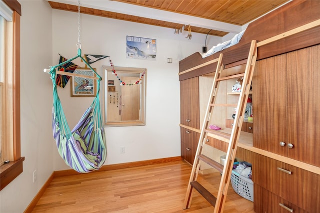 bedroom with light hardwood / wood-style floors, wooden ceiling, and beamed ceiling