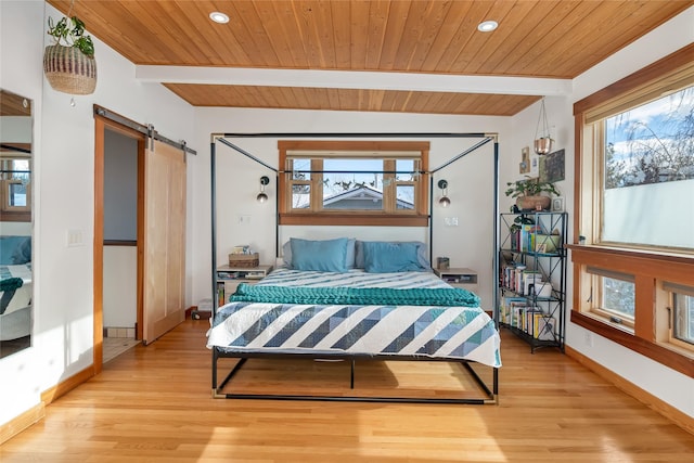 bedroom featuring wooden ceiling, light hardwood / wood-style floors, a barn door, and beamed ceiling