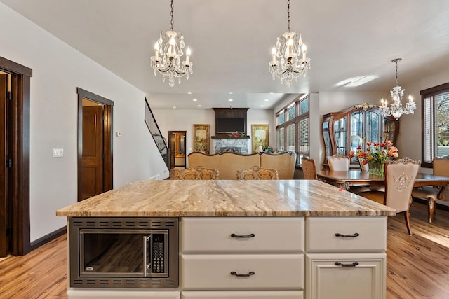 kitchen featuring stainless steel microwave, white cabinets, plenty of natural light, and pendant lighting