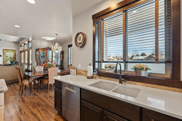 kitchen featuring hardwood / wood-style floors, stainless steel dishwasher, sink, an inviting chandelier, and hanging light fixtures