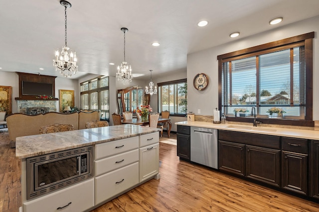 kitchen with decorative light fixtures, sink, stainless steel appliances, and white cabinetry