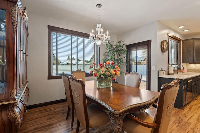 dining room featuring plenty of natural light, sink, a notable chandelier, and light hardwood / wood-style floors